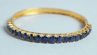 A GOOD 18CT GOLD SAPPHIRE SET BANGLE.