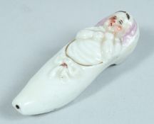 A SMALL PORCELAIN BABY IN A SHOE WHISTLE 2.5ins long.