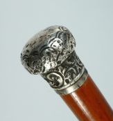 A VICTORIAN CANE with silver handle repousse with scrolls. London, 1887, 34ins long.