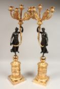 A PAIR OF EMPIRE DESIGN BRONZE AND GILT METAL, FIVE LIGHT CANDELABRA held aloft by bronze