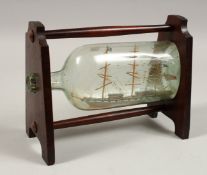 A SHIP IN A BOTTLE on a mahogany stand.