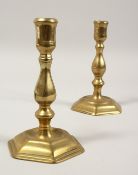A PAIR OF GEORGIAN BRASS CANDLESTICKS on hexagonal bases 6.5ins high.