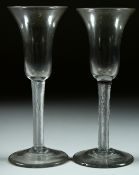 A PAIR OF GEORGIAN WINE GLASSES with inverted shaped bell bowls and air twist stems. 7.25ins high.