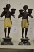 A pair of painted bronze figural candlesticks.