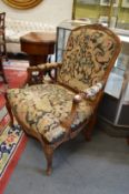 A 19th century French carved walnut open armchair with needlework upholstered back, arms and seat.