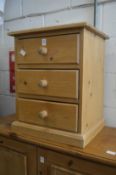 A pine three drawer bedside chest.