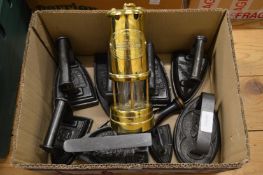 A quantity of old cast iron flat irons and a brass miner’s lamp.