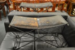 A pair of black leather stools with folding wrought iron frames.