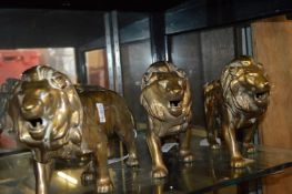 Three large cast brass models of lions.
