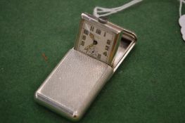 A small silver pop up travelling clock.