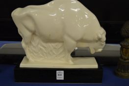 A stylised white pottery model of a bison on a wooden base.