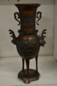 A Japanese bronze vase on three feet with circular base.