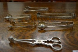 A pair of Georgian silver sugar nips and other silver sugar tongs.