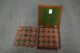 A mahogany box containing 32 cast bronze medallions depicting kings and queens of the realm.