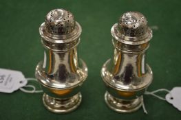 A pair of silver pedestal pepperettes.