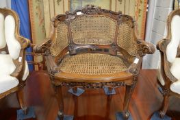A French carved walnut tub armchair with canework back and seat.