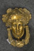 A polished cast brass Minerva’s head door knocker.