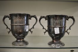 A pair of plated twin handled collage rowing trophy cups, both with engraved inscriptions.