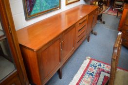 A good mid century teak long low sideboard with four central drawers flanked by two pairs of