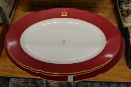 Three large meat plates with maroon rims and armorial decoration.