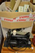 An electric Singer sewing machine and a box of associated textiles.
