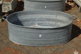A large oval galvanised bath tub.