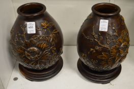 A good pair of Japanese cast bronze vases with moulded floral decoration on hardwood stands.