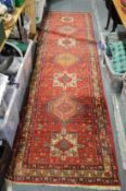A Persian style red ground runner 330cm x 90cm.