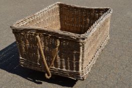 A large wicker laundry basket with cast iron castors.