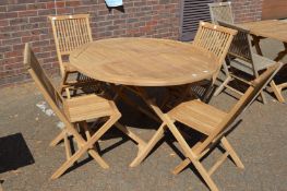 A circular hardwood folding garden table with four chairs.