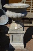 A composite urn shaped planter on pedestal base.