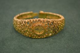 A ladies Omega cocktail watch with pierced bark effect bracelet strap stamped 750.