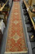 An orange ground Persian style runner 490cm x 70cm.