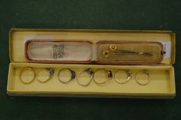 A collection of seven gold and other gem set rings and two tie pins.