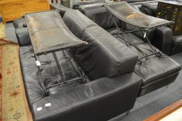 A black leather two seater settee with matching armchair and foot stool.