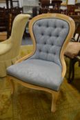 A modern blue upholstered button back bedroom chair.