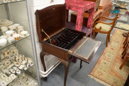 A late Edwardian mahogany writing table with lifting top and folding writing surface.