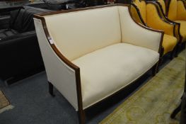 An Edwardian inlaid mahogany two seater high back settee newly upholstered with cream fabric.