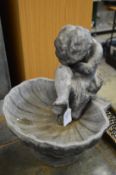 A cast lead cherub and shell bird bath.