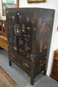 A Chinese lacquer cabinet painted with various symbols including vases, books etc, with two doors