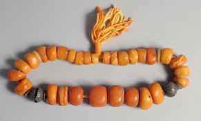 AN ETHNIC LARGE BEADED PRESSED AMBER NECKLACE, with graduating beads and two dividing metal beads,