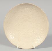 A CHINESE DING WARE DISH with raised decoration depicting a dragon, inscribed to the underside. 20.