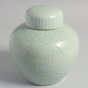 A CHINESE CELADON GLAZE PORCELAIN JAR AND COVER, the body with carved floral decoration, 20cm high.