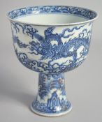 A CHINESE BLUE AND WHITE PORCELAIN PEDESTAL BOWL, painted with dragons above stylised waves, 17cm