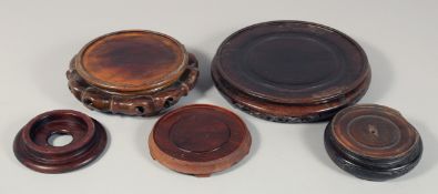 A COLLECTION OF FIVE CHINESE HARDWOOD STANDS, largest 25cm diameter.