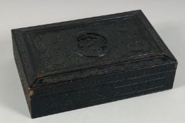 A CHINESE CARVED AND EBONISED WOODEN BOX, the hinged lid carved with central roundel