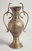 AN ISLAMIC BRASS TWIN HANDLE URN, with engraved decoration and panels of calligraphy, the handles