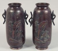 A PAIR OF JAPANESE TWIN-HANDLED BRONZE VASES with relief decoration depicting cranes. 25cm high.