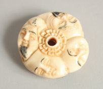 A CHINESE CARVED BONE NETSUKE with faces. 1.5ins diameter.