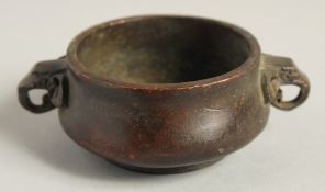 A SMALL CIRCULAR BRONZE CENSER with elephant handles. 2.75ins diameter.